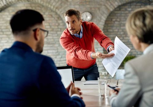 Displeased candidate discussing about his resume with human resource team during job interview in the office.