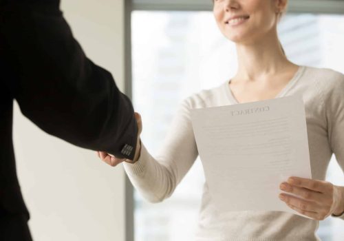 Female business leader holding contract document and shaking hand with colleague before or after negotiation. Businesswoman concluding agreement, starting partnership, accepting offer. Close up view